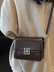Retro dark brown leather crossbody square bag with silver metal buckle on a beige top