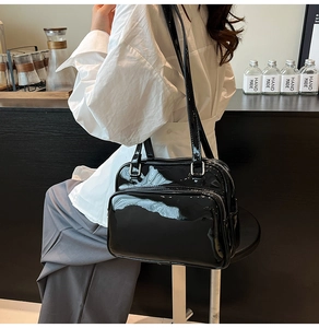 Detail of black patent leather bag featuring multi-layer silver zippers and glossy finish