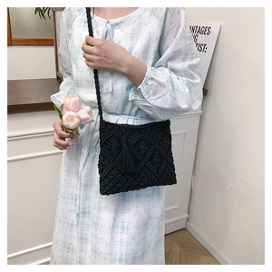 Detail of black handmade woven crossbody bag with geometric diamond texture and tassels