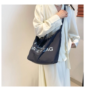 Detail of navy blue tote bag showing refined stitching and embroidery on nylon fabric
