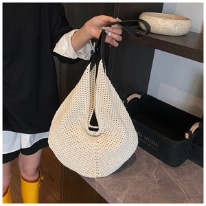 Detail of hand-woven cream hobo bag featuring adjustable black leather shoulder strap