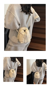 Detailed view of cream nylon drawstring crossbody bag with embroidered logo and strap