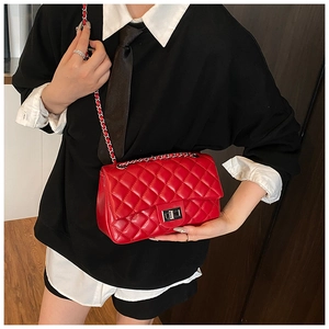 Detail of red quilted crossbody bag with silver metal turn-lock and leather chain strap