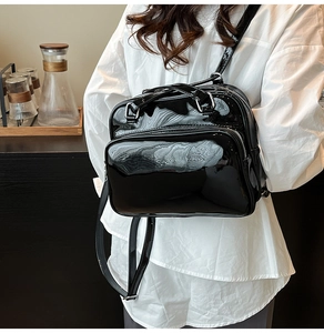 Detail of black glossy faux leather mini backpack with silver metal zippers and hardware