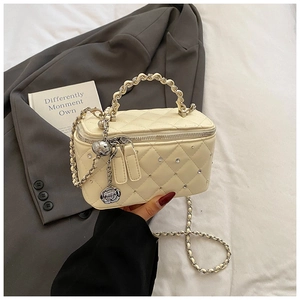 Detailed close-up of beige quilted crossbody bag with silver chain and floral charms