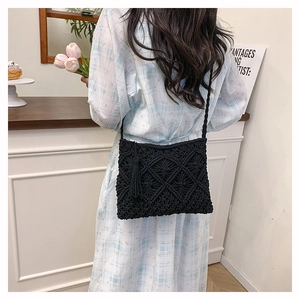 Detail view of black crochet shoulder bag with intricate diamond patterns and fringe trim