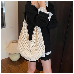 Close-up of beige woven hobo bag featuring black leather strap and textured mesh pattern