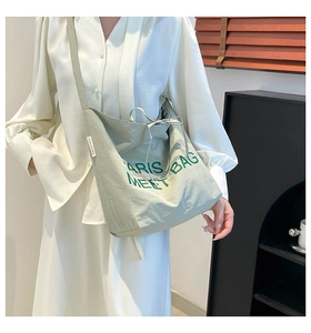 Detail of light green canvas tote bag with drawstring closure and wide shoulder strap