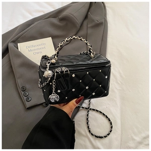 Detail of black quilted vanity bag with silver studs and rose zipper charm handle