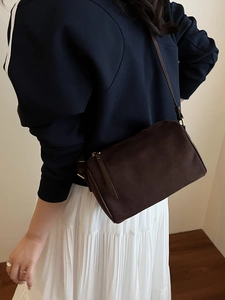 Brown suede crossbody pillow bag with long tassel zipper and slender shoulder strap