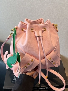 Pink lychee grain leather bucket bag with drawstring closure and floral charm