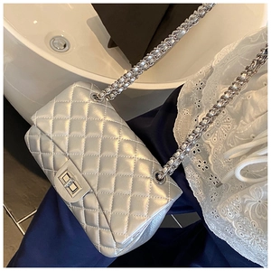 Close-up of silver quilted crossbody bag featuring a metal chain strap and twist-lock clasp