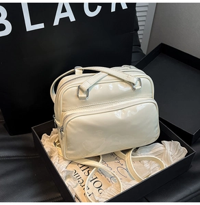 Detail of off-white patent leather handbag with silver zippers and multi-pocket structure