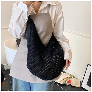 Detail of black crochet hobo bag with hollow mesh design and soft woven texture