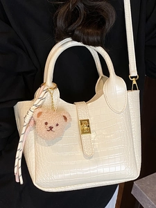 Weiße Eimertasche mit Krokodilmuster, Bärenanhänger und goldenem Drehverschluss-Detail
