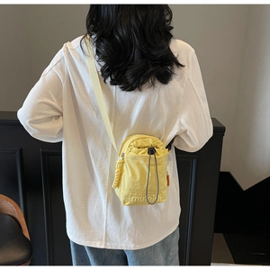 Close-up of yellow lightweight nylon crossbody bag with drawstring closure and brand logo