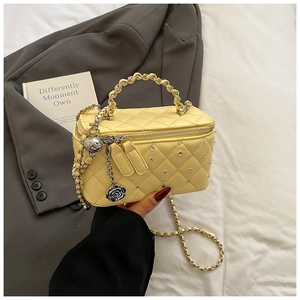 Detailed close-up of yellow quilted bag with rhinestones, chain handle and rose pendant