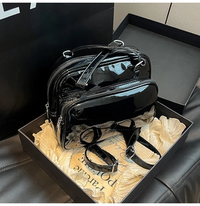 Detailed shot of black patent leather multi-way backpack and handbag in packaging