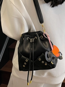 Minimalist black lychee leather bucket bag featuring a unique elephant charm with drawstring
