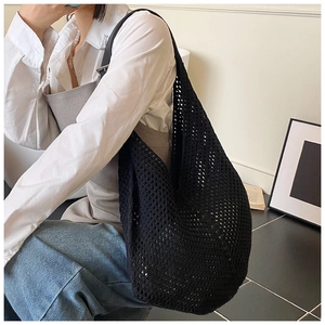 Detailed close-up of a large black crochet woven crescent bag worn on a woman's shoulder