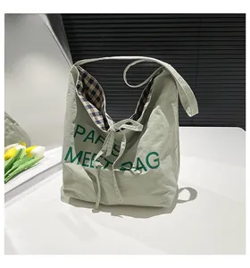 Detail of light green hobo tote bag featuring checkered lining and ribbon bow tie closure