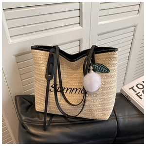 Detailed close-up of straw woven tote bag featuring black Summer embroidery and leaf charm