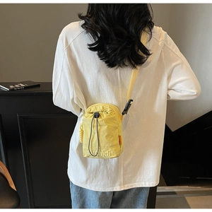 Back view of a vibrant yellow drawstring crossbody phone bag worn by a model