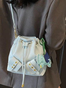 Light blue pebbled leather bucket bag with drawstring closure and elephant charm accessory