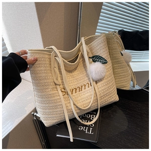 Close-up of Summer straw tote bag featuring refined embroidery and plush charm detail