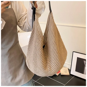 Close-up of woven straw hobo bag with contrast black leather strap for women
