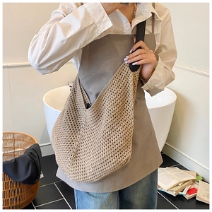 Detail of beige crochet hobo bag with hollow mesh pattern and black leather strap