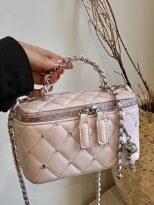 Pink quilted crossbody bag with silver studs and chain strap in soft natural light