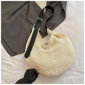 Detailed close-up of cream woven hobo bag featuring contrast black adjustable leather strap