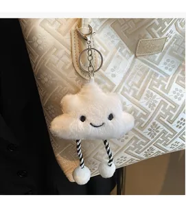 Vue détaillée d'un charm nuage en peluche blanc avec visage souriant sur un sac cabas