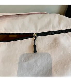 Detailed view of the smooth black zipper and pink nylon fabric on a daily canvas bag