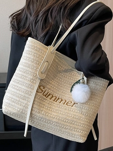 Summer straw tote bag in cream with embroidery and pearl charm shown on model shoulder