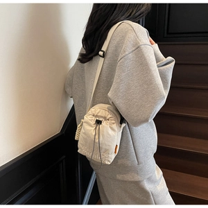 Detail of minimalist cream drawstring crossbody bag on model for casual daily wear