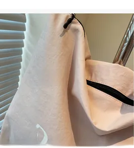 Detail of pink canvas drawstring bag with black zipper and printed white letters