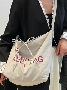 Minimalist off-white canvas tote bag with purple lettering and ribbon bow detail