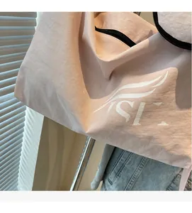 Detailed texture of pink nylon fabric and printed white wing logo on large tote bag