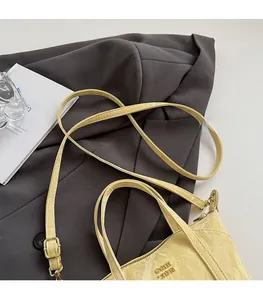 Détail du petit sac cabas en cuir verni beige plissé avec logo métallique et bandoulière réglable
