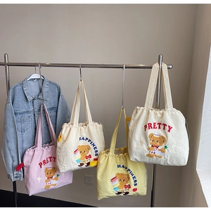 Detailed close-up of colorful canvas tote bags featuring cute bear embroidery accents