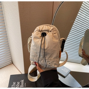 Close-up of white nylon crossbody bag with mulaidi embroidery and orange side label