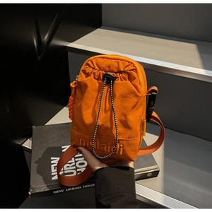 Detail of bright orange waterproof nylon crossbody bag with drawstring and buckle