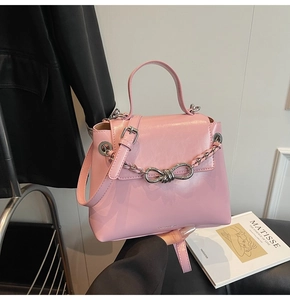 Detail of pink leather small square bag with silver metal chain and knot buckle detail