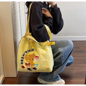 Detailed view of yellow tote bag featuring cute bear embroidery and HAPPINESS text print