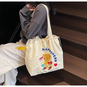 Detail of cute bear embroidery and blue Happiness text on cream canvas tote bag