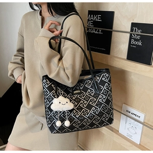 Détail d'un sac cabas à motifs géométriques noir et blanc avec un charme nuage en peluche