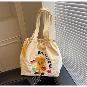 Detail of beige canvas tote bag with cute bear patch and blue Happiness embroidery