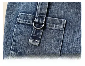 Detail of blue denim shoulder bag featuring a utility pocket and metallic D-ring buckle